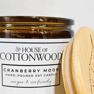 Candle jar with wooden lid labeled 'House of Cottonwood Cranberry Moon' with bamboo lid