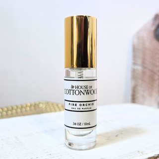 Perfume bottle labeled 'House of Cottonwood' on a light surface with a blurred background
